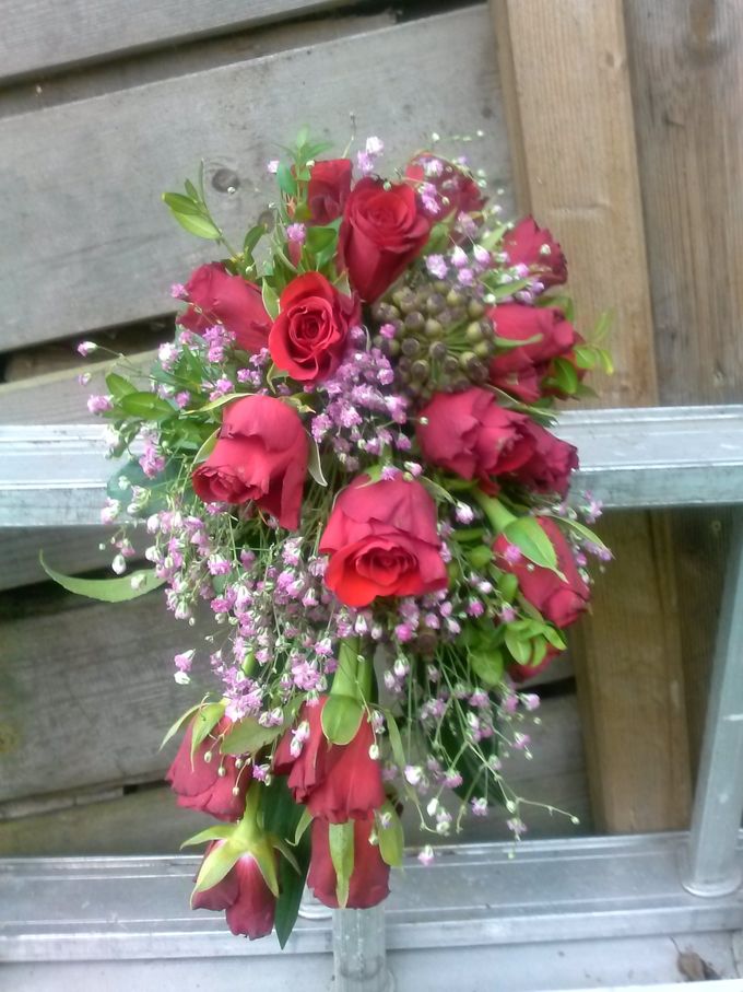 Bruidsboeket met rode rozen, gipskruid, hederabesjes, buxestakjes en aspedistrablad.