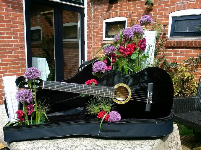 Gitaar in koffer met bloemen en muziekstukken